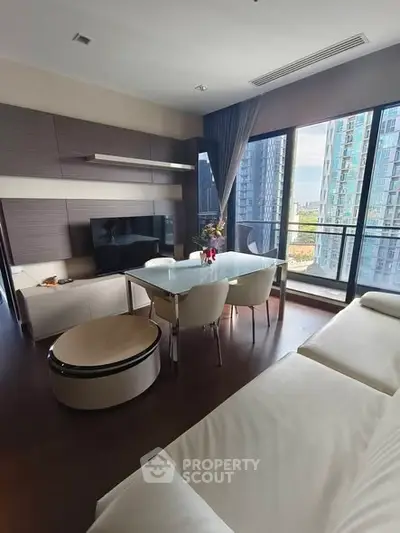 Modern living room with large windows and city view, featuring sleek furniture and elegant decor.