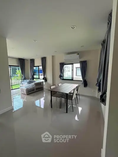 Spacious modern living room with large windows and sleek dining area