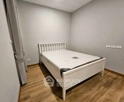 Cozy minimalist bedroom with wooden flooring and a white bed frame, perfect for restful nights.