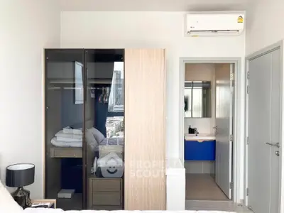 Modern bedroom with sleek wardrobe and ensuite bathroom in urban apartment.