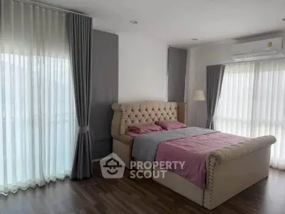 Spacious bedroom with elegant bed and natural light through large windows.