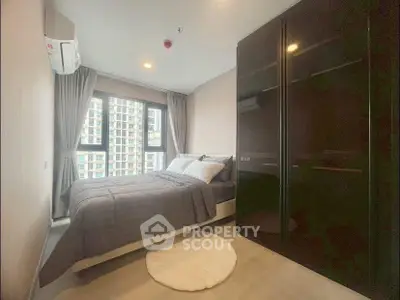 Modern bedroom with large window and sleek wardrobe in urban apartment.