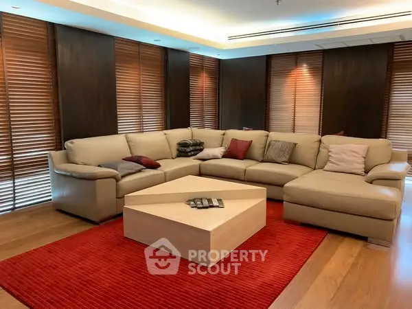 Luxurious living room with modern sectional sofa and elegant wooden blinds.