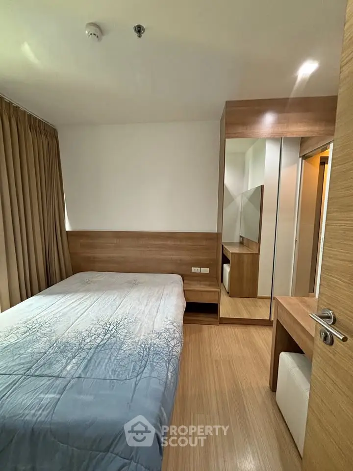 Cozy bedroom with wooden accents and mirrored wardrobe in modern apartment.