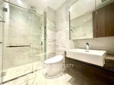 Luxurious modern bathroom with marble tiles and sleek fixtures, featuring a spacious glass shower and elegant vanity.