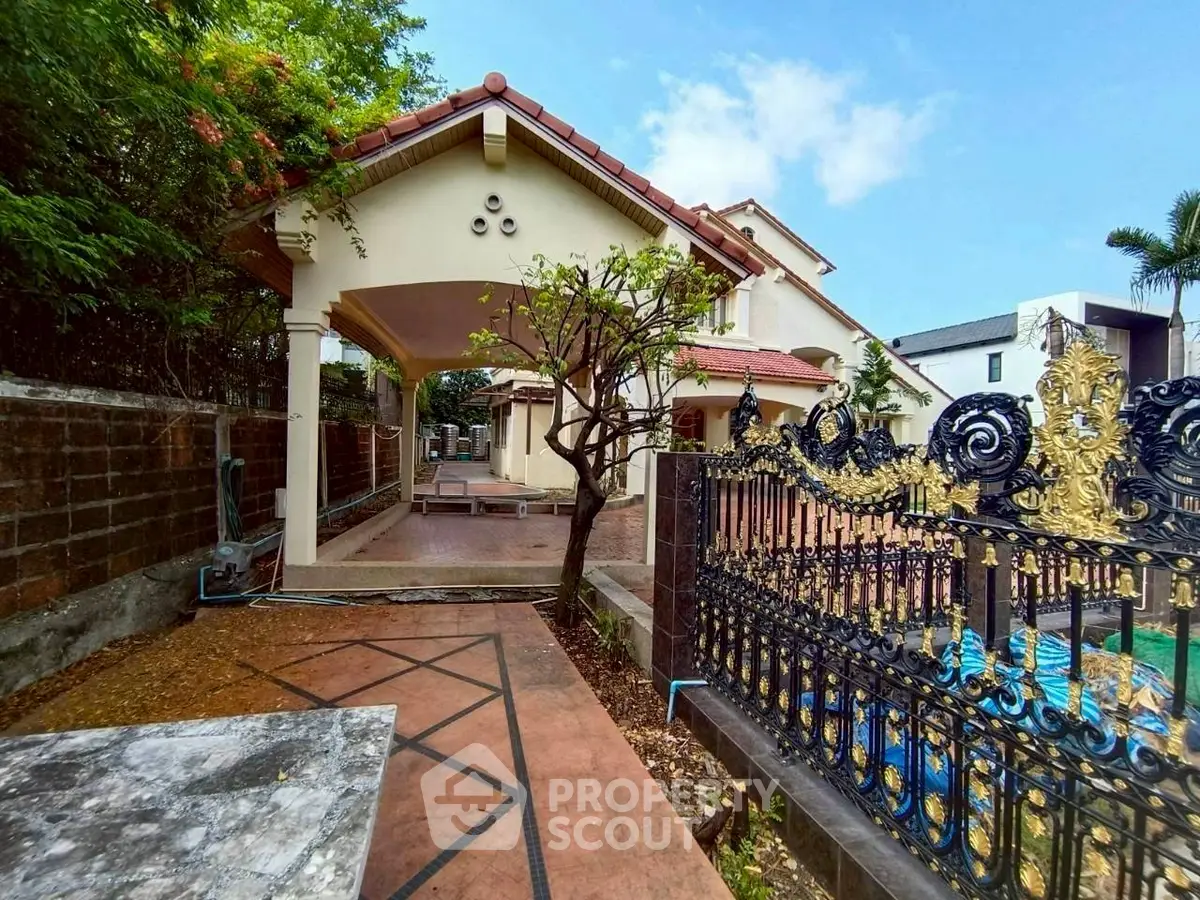 Charming villa with ornate gate and lush garden, perfect for serene living.