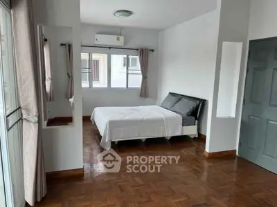 Spacious bedroom with parquet flooring and large windows in modern apartment