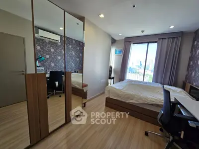 Spacious bedroom with modern decor and city view, featuring a large mirror and stylish furnishings.