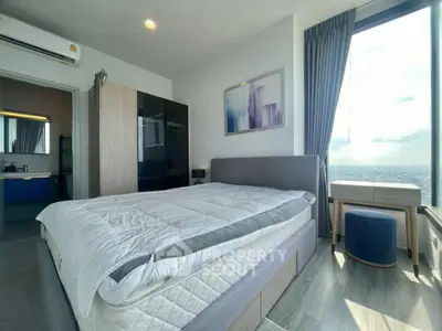 Modern bedroom with large window offering stunning city view, featuring stylish decor and ample natural light.