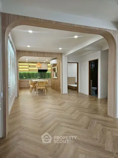 Spacious open-plan living area with modern kitchen and dining space, featuring elegant wood flooring.