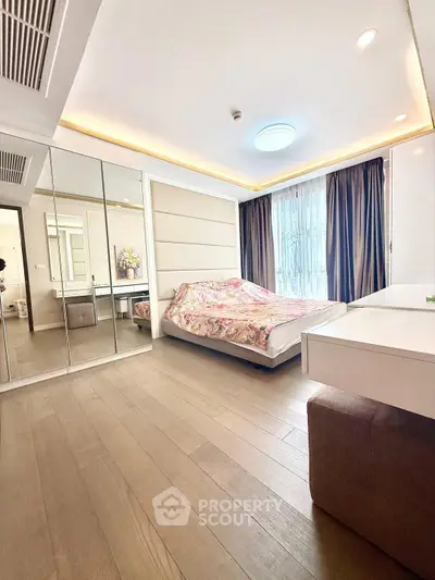 Spacious bedroom with mirrored closet and modern decor