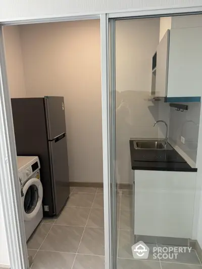 Modern compact kitchen with washing machine and fridge in sleek apartment