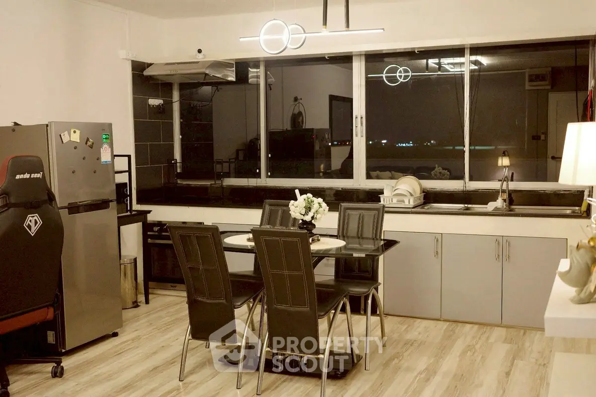 Modern kitchen with dining area, featuring sleek appliances and stylish lighting in a contemporary open layout.