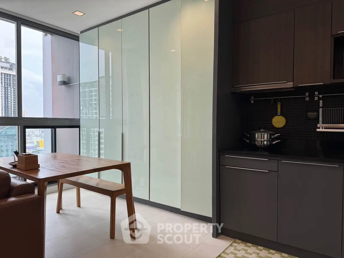 Modern kitchen with sleek cabinets and dining area in high-rise apartment with city view.