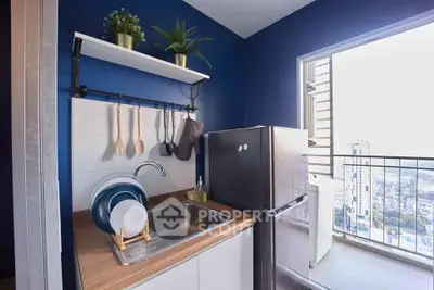 Modern kitchen with blue walls, compact design, and balcony view in urban apartment.