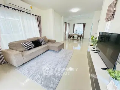 Spacious living room with modern decor and natural light, featuring a cozy sofa and sleek TV setup.