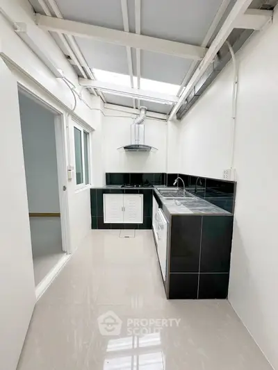 Modern kitchen with sleek black and white design, featuring a gas stove and ample natural light.