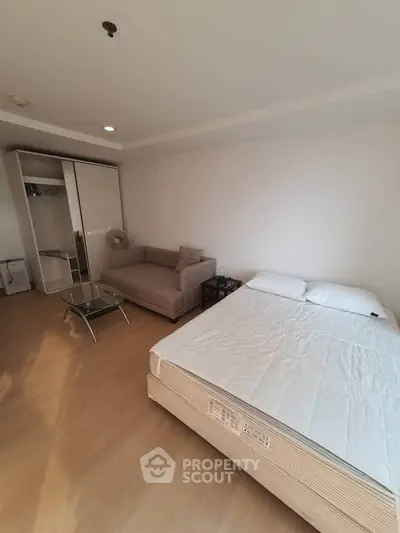 Spacious bedroom with cozy sofa and modern wardrobe in a bright apartment.