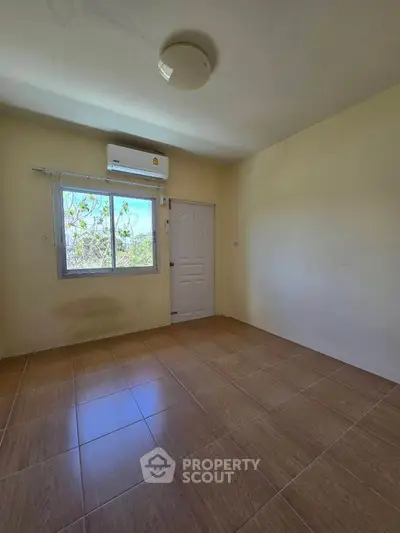 Spacious empty room with tiled floor and window, ideal for customization.