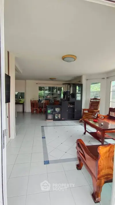Spacious living room with elegant wooden furniture and large windows offering natural light.
