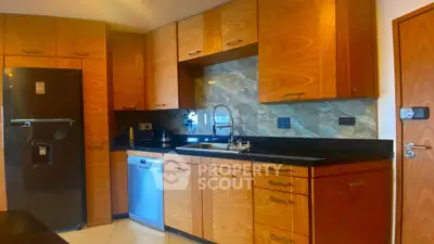Modern kitchen with wooden cabinets, stainless steel appliances, and sleek black countertops.