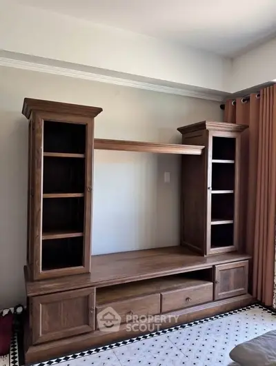 Spacious wooden entertainment center in a well-lit living room with elegant curtains.