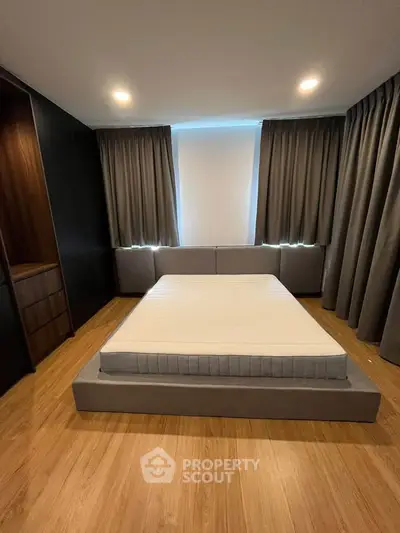 Modern bedroom with minimalist design, featuring a sleek platform bed and elegant wooden flooring.