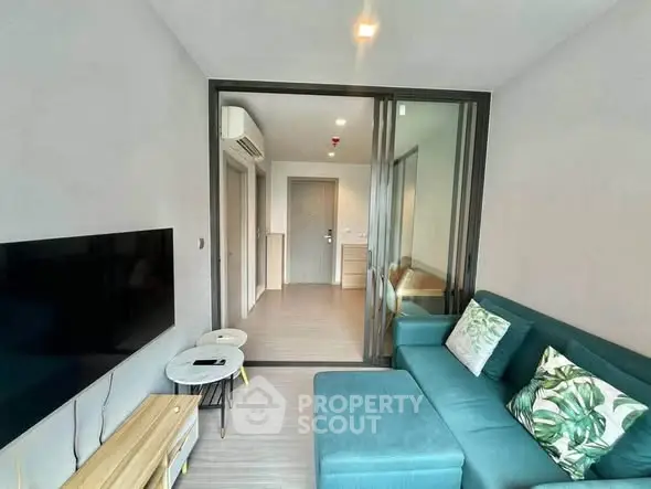 Modern living room with teal sofa and wall-mounted TV in a stylish apartment.