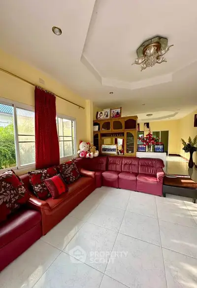 Spacious living room with red leather sofas and large window view