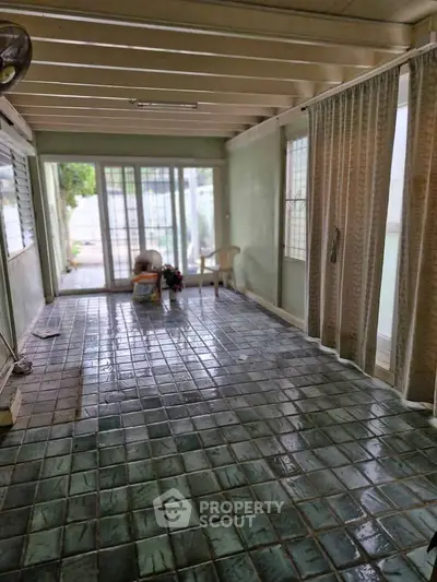 Spacious sunroom with tiled floor and sliding glass doors leading to a garden area.