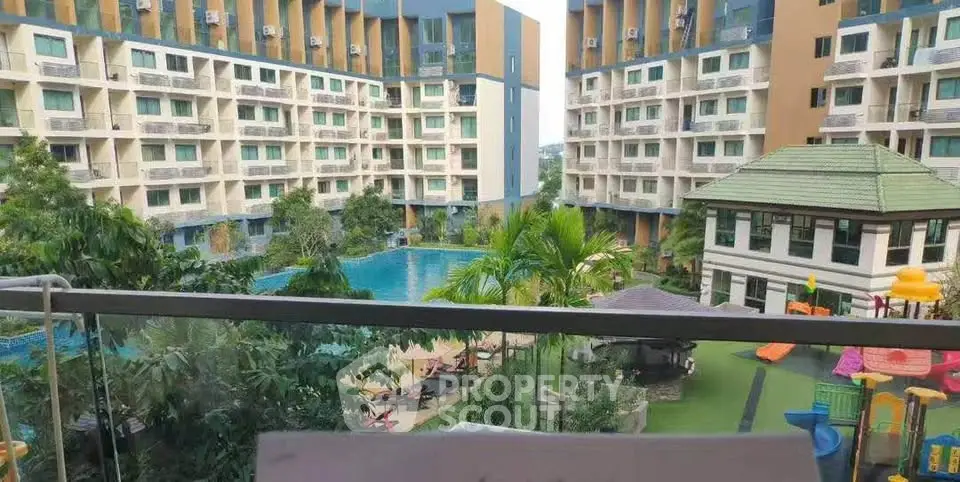 Stunning view of modern apartment complex with pool and lush garden from balcony.