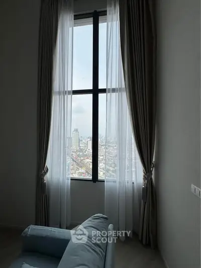 Stunning city view from a modern living room with elegant curtains and cozy seating.