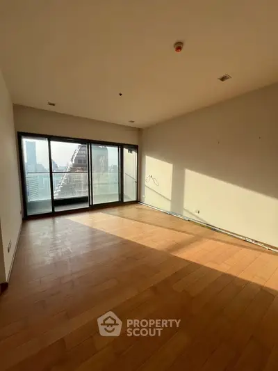 Spacious empty room with large windows and wooden flooring, offering a bright and airy atmosphere.