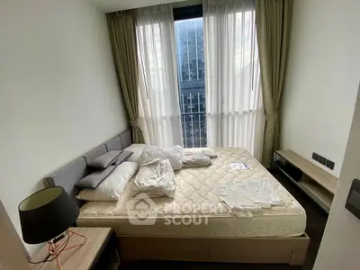 Modern bedroom with large window and stylish furnishings in urban apartment.