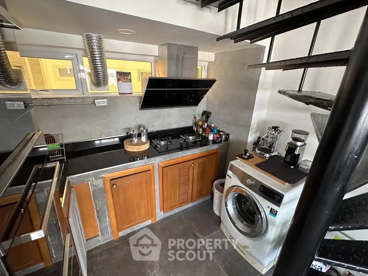 Modern kitchen with wooden cabinets, gas stove, and washing machine in a compact layout.