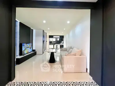 Modern open-plan living room with sleek kitchen, stylish decor, and cozy seating area.