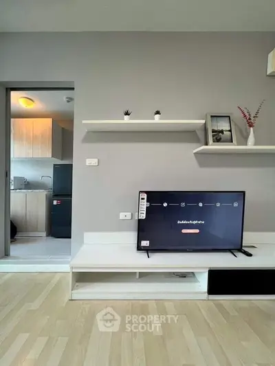 Modern living room with sleek TV setup and open view to stylish kitchen.