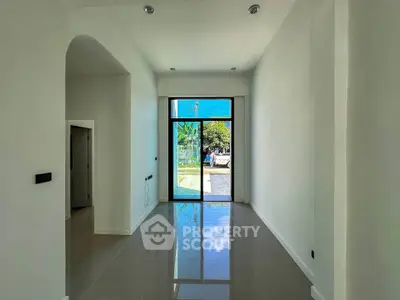 Spacious modern entrance with glossy tiled floor and large window view.