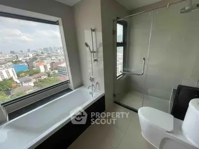 Modern bathroom with city view, featuring bathtub and glass shower enclosure.