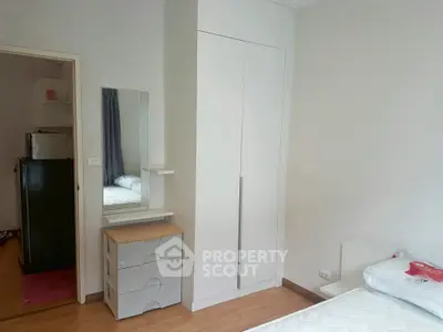 Cozy bedroom with modern wardrobe and dresser, perfect for urban living.