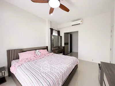 Spacious bedroom with modern decor and ceiling fan, featuring a comfortable bed and ample storage space.