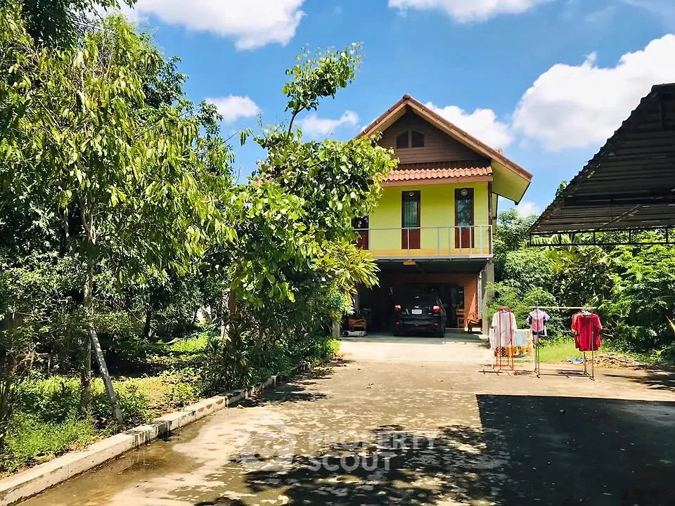 Charming two-story house with lush garden and spacious driveway under a clear blue sky.