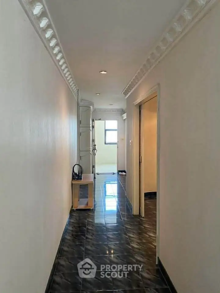 Spacious hallway with glossy tiled flooring and elegant crown molding.