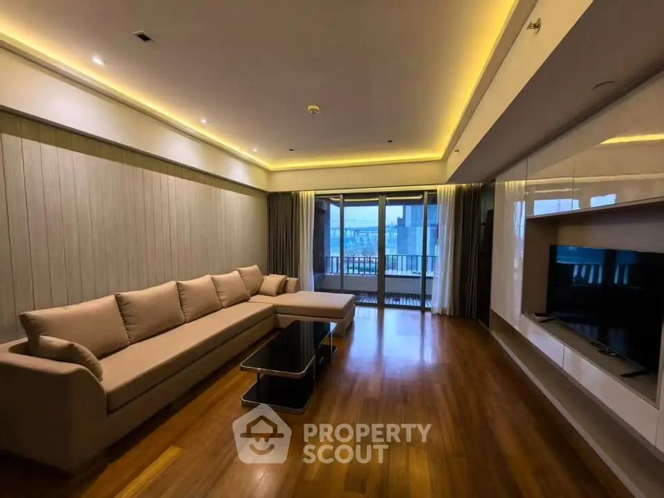Spacious living room with modern lighting and large windows leading to a balcony.