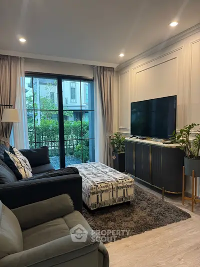 Stylish living room with modern decor and garden view, featuring cozy seating and large TV.
