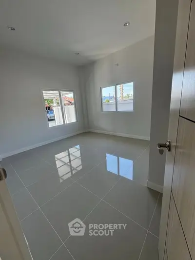 Spacious empty room with glossy tiled floor and large windows