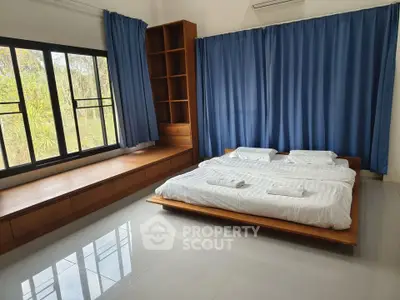 Spacious bedroom with modern design, large windows, and blue curtains.