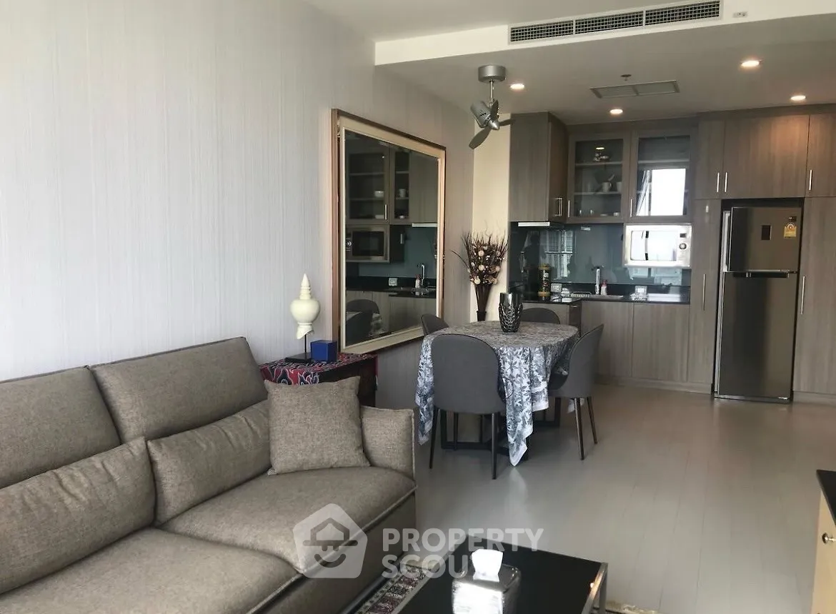 Modern open-layout living room and kitchen with stylish furniture and appliances.