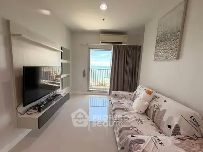 Modern living room with ocean view, sleek TV setup, and cozy sofa in a bright apartment.