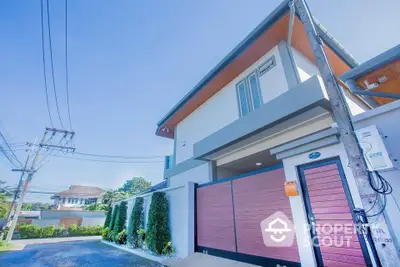 Modern two-story house with sleek design and wooden gate in suburban neighborhood.